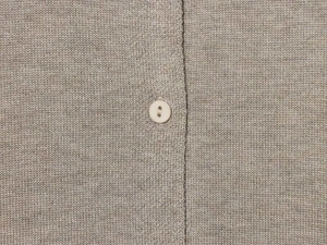 Close-up of oatmeal knit cardigan showing fine texture and white button detail