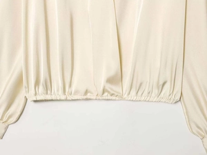 Detail of champagne satin shirt hem with elastic waistband and smooth silk texture