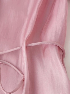 Macro shot of smooth pink satin fabric detail and silk bow tie ribbon on a shirt