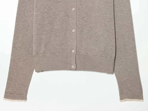Close-up of knit cardigan with wood buttons and delicate white lace cuffs on sleeves
