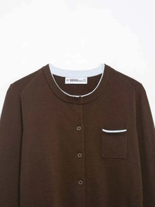 Detail of brown knit cardigan featuring light blue contrast trim on round neck and pocket