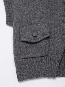Detail of dark grey knit vest featuring textured fabric flap pocket and matching button
