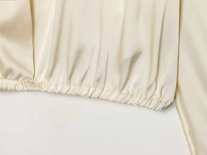 Detailed close-up of cream satin fabric with elegant elastic pleated cuff and neat stitching