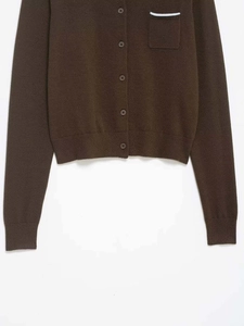 Detail of dark brown knit cardigan showing ribbed edges and chest pocket with white stripes