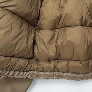 Detailed macro view of the wide quilted puffer jacket with elastic hem and brown fabric