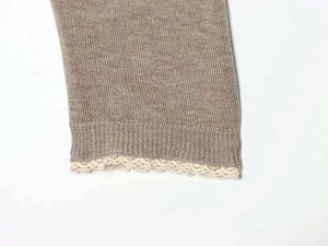 Detail of oatmeal knit cardigan cuff featuring delicate off-white lace trim and ribbed edges