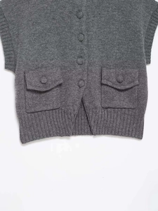 Detailed view of dark grey knit vest with flap pockets and fabric-covered buttons
