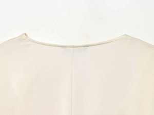 Detailed close-up of cream lantern sleeve blouse neckline with fine woven texture