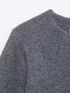 Detailed macro view of dark grey knitted cardigan fabric with soft wool texture and stitching