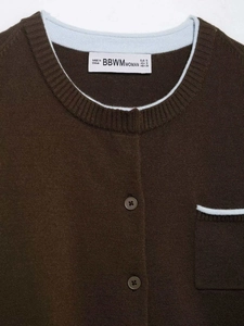 Detail shot of a dark brown knit cardigan with blue contrast trim and brand neck label