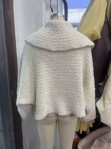 Close-up of thick white textured boucle knit fabric on a stylish short autumn jacket