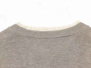 Detailed view of taupe knit cardigan showing white lace scalloped neckline trim