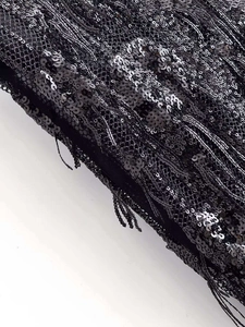 Détail des paillettes noires scintillantes et des franges sur cette robe asymétrique