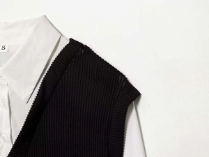 Détail du gilet en maille côtelée noire sur une chemise en popeline blanche à col pointu