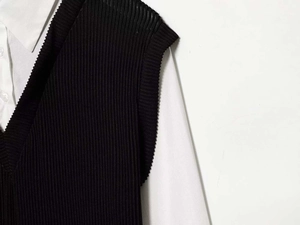 Détail rapproché d'un pull sans manches en tricot noir sur une chemise blanche à col