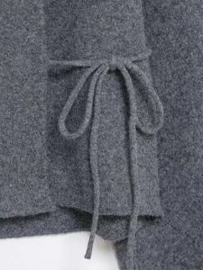 Macro detail of dark grey knit cardigan fabric with textured tie-up fastener