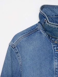 Detail view of denim jacket showing collar stitching and premium fabric texture