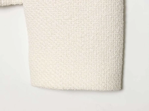 Macro shot of off-white bouclé tweed fabric texture for women's casual jacket