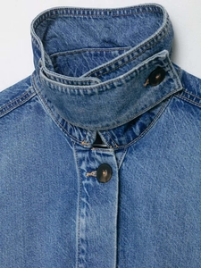 Close-up of high-neck denim jacket with tortoiseshell buttons and premium stitching