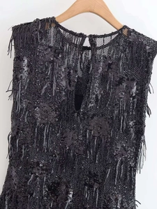 Détail d'une robe noire à paillettes avec de longues franges et dos goutte d'eau