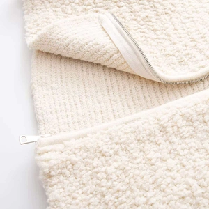 Detail of a creamy white teddy fleece jacket featuring a durable metal zipper closure