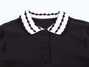 Detail of black polo collar with black and white wavy texture and ruffle edges