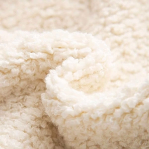 Macro texture of soft white bouclé knit fabric showing thick curly yarn detail