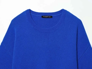 Détail du pull en maille bleu roi avec col rond et étiquette de marque textile
