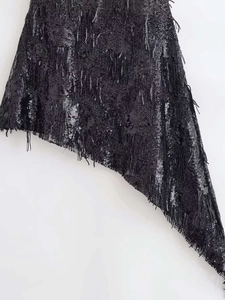 Détails de la robe noire à paillettes avec franges et ourlet asymétrique pour la fête