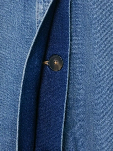 Detail of dark resin button and contrast denim patchwork on fashionable autumn jacket