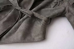 Dettaglio della giacca in camoscio grigio con cintura e lacci con occhielli in metallo