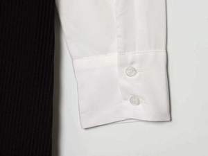 Détail des poignets en popeline blanche avec boutons transparents et tricot côtelé noir