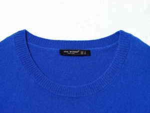 Détail macro du col rond du pull en maille bleu roi et de l'étiquette de marque