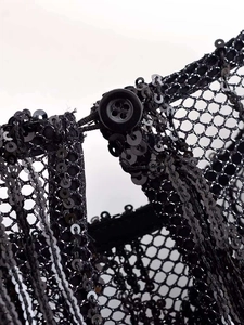 Détail macro de paillettes noires sur tissu mesh avec fermeture à bouton rond