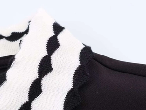 Close-up of contrast knit polo collar featuring decorative black and white scalloped edges