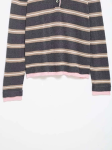 Detail view of striped polo knitwear with contrast buttons and pink layered cuffs