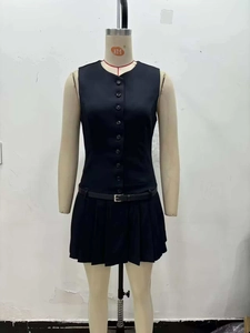 Detail view of black sleeveless pleated dress with button bodice and waist belt