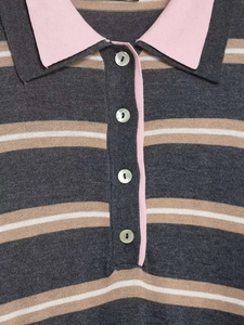 Detail of striped knit polo shirt featuring pearl buttons and a contrast pink collar