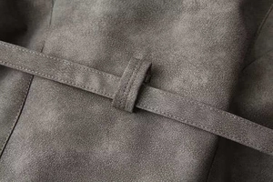 Dettaglio ravvicinato della cintura regolabile e della texture in camoscio del cappotto