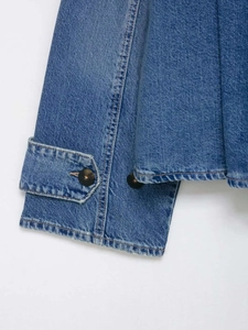 Detail shot of denim jacket cuff with tortoiseshell button and premium stitching texture
