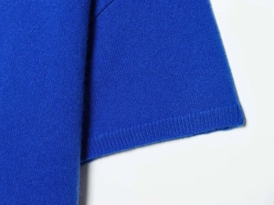 Détail des poignets en maille côtelée sur un pull bleu Klein minimaliste à col rond pour femme