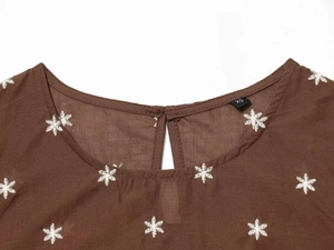 Nahaufnahme der braunen Ärmellosen-Bluse mit weißer Stickerei und Tropfen-Ausschnitt-Detail
