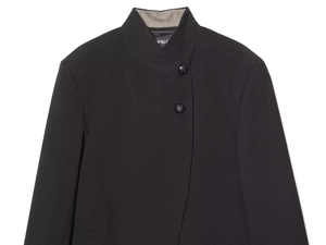 Detail of a black stand collar blazer with textured fabric and asymmetrical button closure