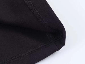 Close-up of overlock stitching detail on the black hem of a cotton-blend POLO top