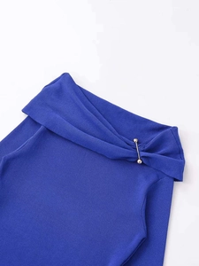 Close-up of royal blue ribbed knit top featuring an elegant twist neckline and gold metal bar