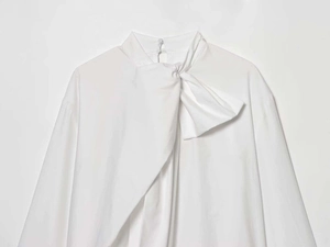 Détail de la chemise en popeline blanche avec col montant et un nœud élégant asymétrique