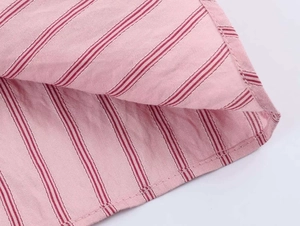 Nahaufnahme von rosa-rot gestreiftem Baumwollstoff mit feinen Nähten und Materialstruktur