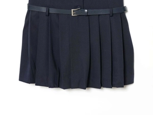 Detailed close-up of navy pleated skirt with matching belt and fine texture detail