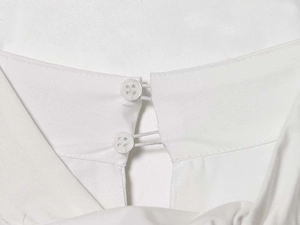 Détail de l'encolure de chemise en popeline blanche avec double bouton et bride