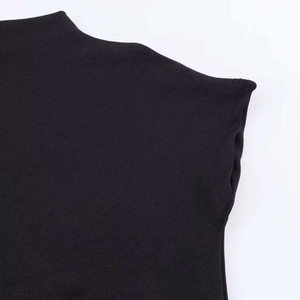Detail of a minimalist black knit mini dress featuring a mockup high neck and premium texture